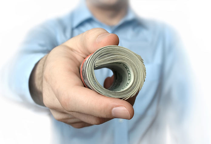 a person offering a bundle of cash